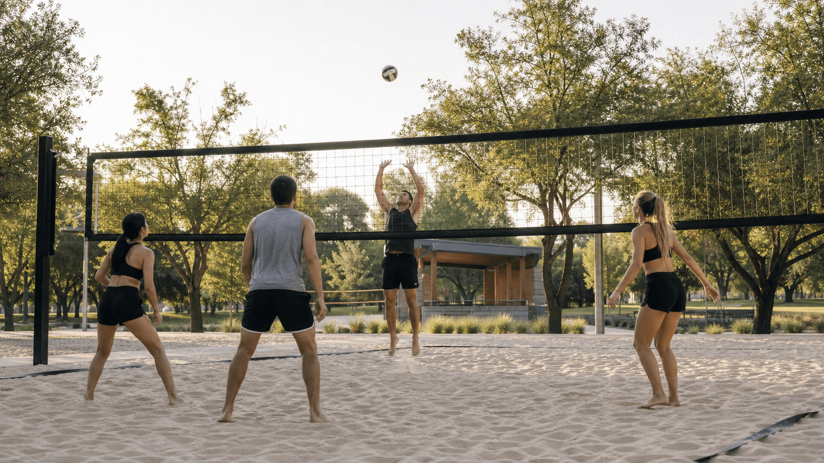 Jugadores disfrutando un partido de voleibol en una cancha de arena dentro de un parque urbano
